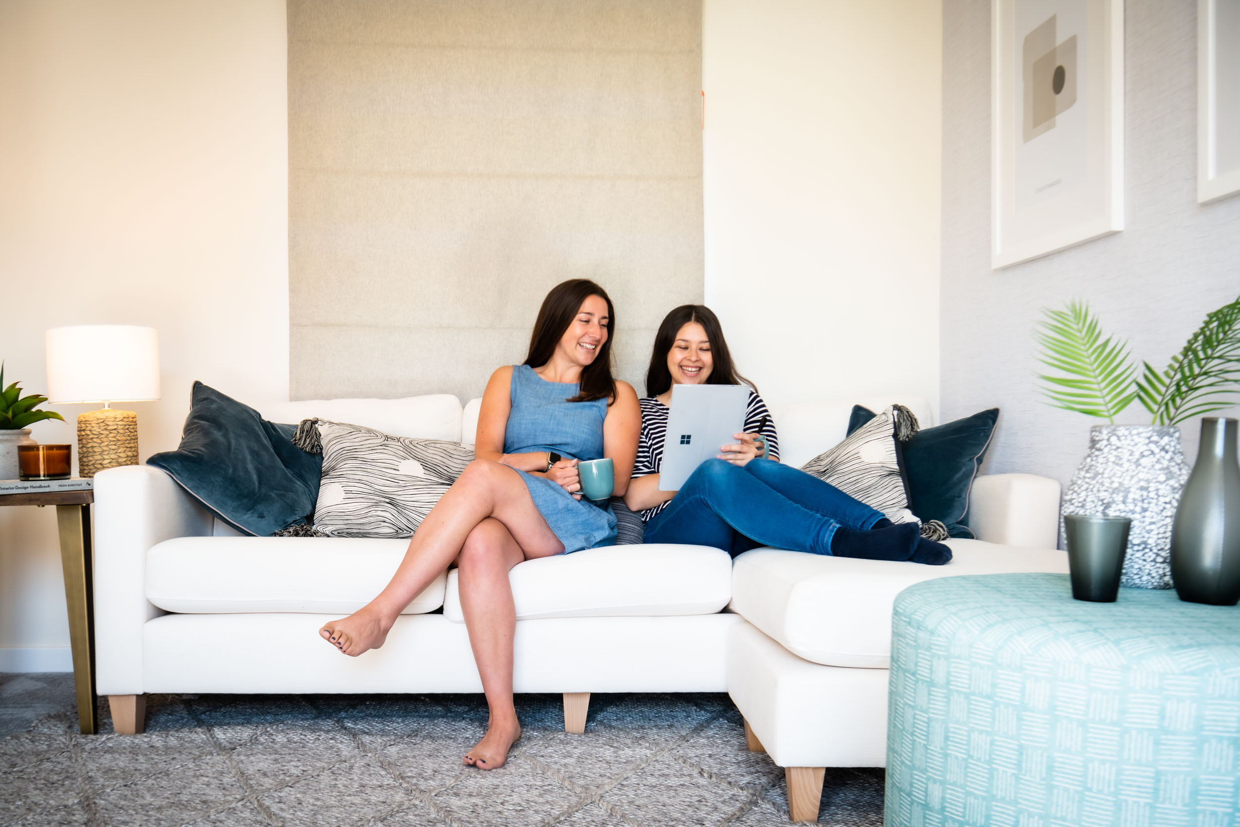 A lifestyle photo of a couple on a sofa. They are smiling and looking at a tablet together.